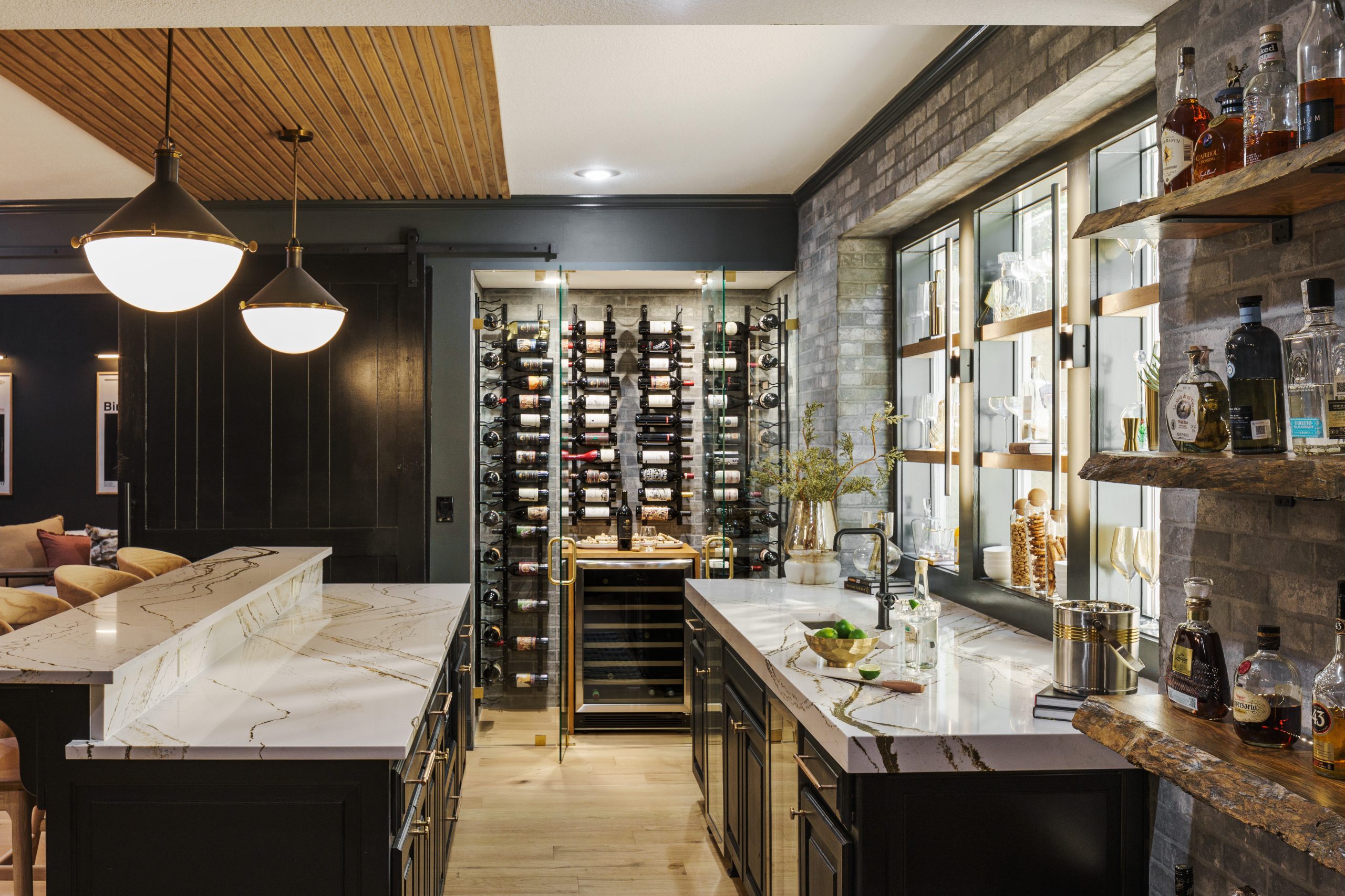 Bar setting with dual counters, sink, wine rack, and pendant lighting